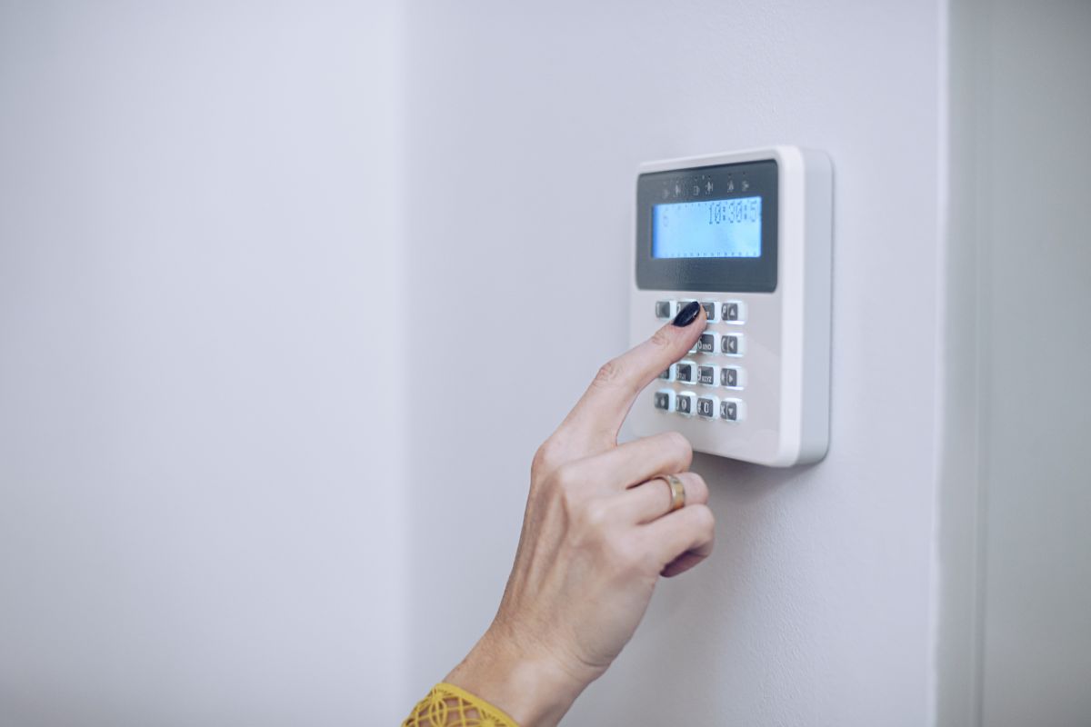 A person activating a security system by pressing a button on a wall, ensuring safety and protection.