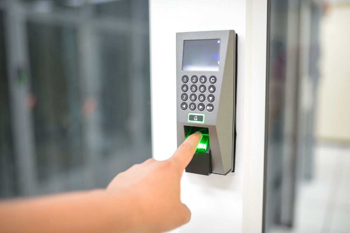 A person is placing their finger on a fingerprint reader installed on a door for access.